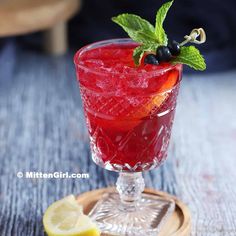 a red drink garnished with mint and lemon