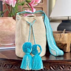 a pair of blue shoes sitting on top of a wooden table next to a bag