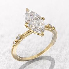 a pear shaped diamond ring with three small diamonds on the band, set in 18k yellow gold