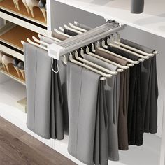 an organized closet with clothes and shoes hanging on the rails, in front of a white cabinet