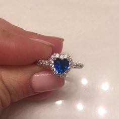 a woman's hand holding an engagement ring with a blue stone in the center