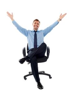 a man sitting on top of an office chair with his hands up in the air