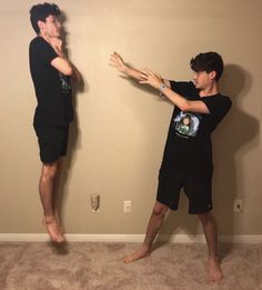 two young men standing in front of a wall