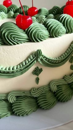 a green and white cake with cherries on top