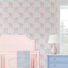 a baby's room decorated in pink and blue with flowers on the wallpaper