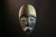 a wooden mask with two faces on it's face and one has eyes closed