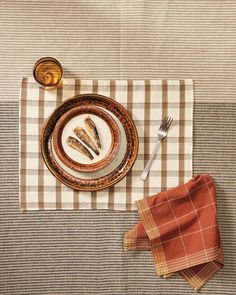 a plate with fish on it sitting next to a fork and knife, along with two napkins