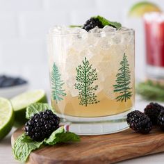 a glass filled with ice and blackberries on top of a cutting board