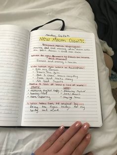 an open notebook with writing on it and someone's hand next to the book