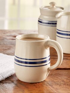 two coffee mugs sitting on top of a wooden table next to a white towel