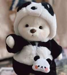 a small stuffed panda bear with a black and white outfit on it's chest