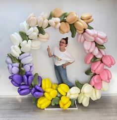 a woman standing in front of a bunch of balloons that look like flowers and leaves