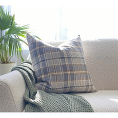 a plaid pillow on a couch next to a potted plant