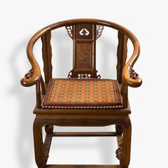 a wooden chair with an orange and blue patterned seat pad on it's back