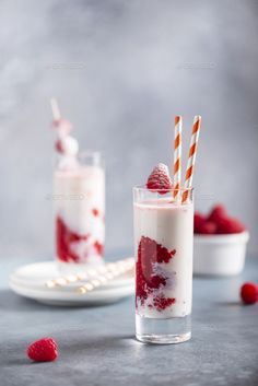 two glasses filled with raspberry milkshake and topped with strawberries - stock photo - images