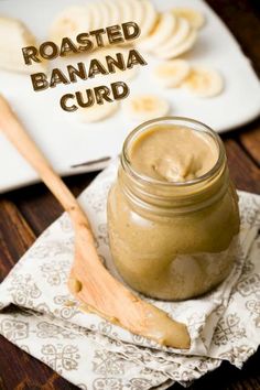 a jar filled with peanut butter sitting on top of a napkin next to sliced bananas