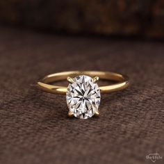 a close up of a diamond ring on a brown surface with the center stone in yellow gold