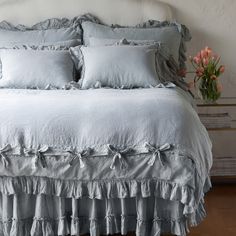 a white bed with ruffled sheets and pillows