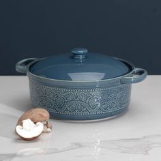 a blue casserole sitting on top of a white counter next to a mushroom