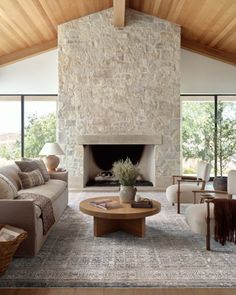 a living room filled with furniture and a fire place in front of a stone wall