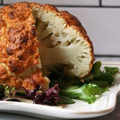 there is a cauliflower that has been cut in half on a plate with lettuce