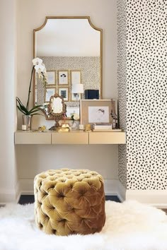 a vanity with a mirror, stool and pictures on the top shelf in front of it