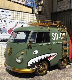 a green van with a shark's mouth painted on the side and gold rims