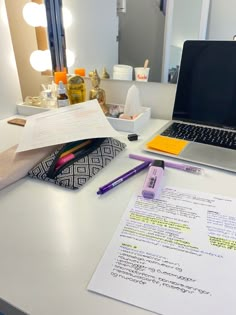 a laptop computer sitting on top of a desk next to a notepad and pen