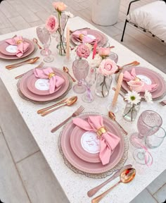 the table is set with pink and gold plates, silverware, and napkins