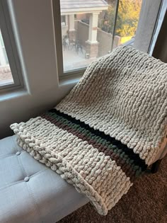 a blanket sitting on top of a couch next to a window with a patio in the background