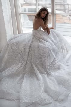 a woman in a white dress sitting on a window sill