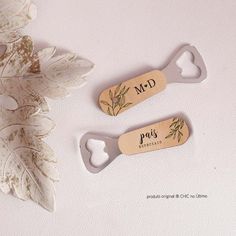 two bottle openers sitting on top of a white table next to a leafy plant