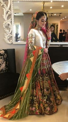 a woman in a colorful dress standing next to a mirror