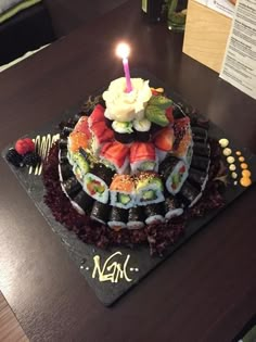 a sushi cake with a lit candle on it sitting on top of a table