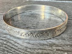 Brand new style! Beautiful botanical floral design, with a nice thick, sturdy weight.  Dimensions: .375" x .059"  I prefer to make all bangles to order in your exact size, so please allow up to 2 weeks to receive your order. I can also make any piece in a round or oval open cuff style so that it is fully adjustable. You can determine your bangle size in two ways: 1) You can measure the length around the widest part of your hand (circumference) or, 2) Measure the diameter (length from inside edge to inside edge of the circle) of an existing bangle. Method 1: Bring your thumb and pinky finger together. Use a piece of string or a measuring tape to measure around the widest part of your hand (where the bangle would have to slide over), and provide that measurement to me in inches or millimeter Victorian Silver Bangle With Intricate Design, Victorian Silver Engraved Bangle, Ornate Antique Silver Bangle Bracelet, Handmade Ornate Antique Silver Bangle, Vintage Silver Bangle, Collectible, Antique Silver Jewelry, Botanical Pattern, Sterling Silver Bangles, Silver Bangles