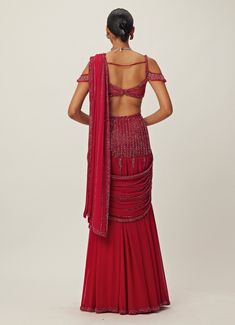 Step into the spotlight and radiate confidence and grace with the Ruby Red Pre-Draped Crystal Embroidered Georgette Saree Set, a captivating blend of elegance and modern style. Crafted from luxurious georgette, the pre-draped red saree features intricate tonal hand embroidery adorned with cutdana and crystal embellishments, adding a touch of sparkle and sophistication. Paired with an off shoulder jewelled blouse embellished with matching crystal details which adds a chic detail. Perfect ready to