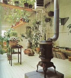 an old fashioned stove sitting in the middle of a room filled with potted plants