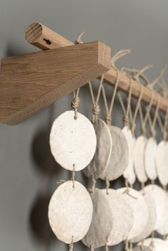 a wind chime hanging from the side of a wooden rack with white discs on it