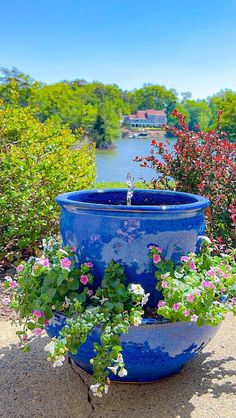 a blue planter filled with flowers next to a river