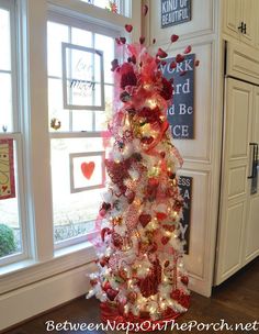 a white and red christmas tree in front of a window