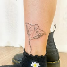 a woman's foot with a tattoo of a stingfish on her left leg