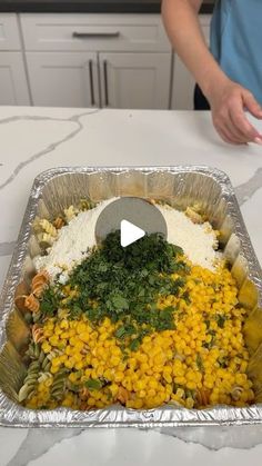 a person standing in front of a pan filled with food on top of a counter