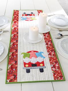 a table runner with a red car on it and two white candles in the center