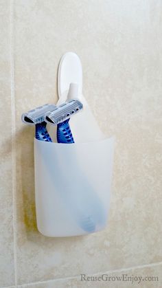 two toothbrushes in a cup hanging on the wall