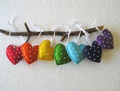 colorful hearts hanging from a branch with white polka dots on them and tied to the wall