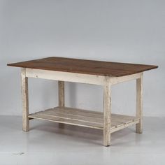 an old wooden table with shelf underneath it on a white floored room wall background