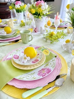 the table is set with plates, cups and vases