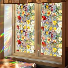 the sun is shining in front of a window with flowers and leaves on it,