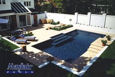 a backyard with a pool surrounded by lawn furniture