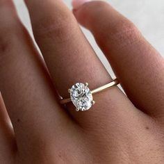 a woman's hand with a gold ring and a diamond in the middle, on top of her finger